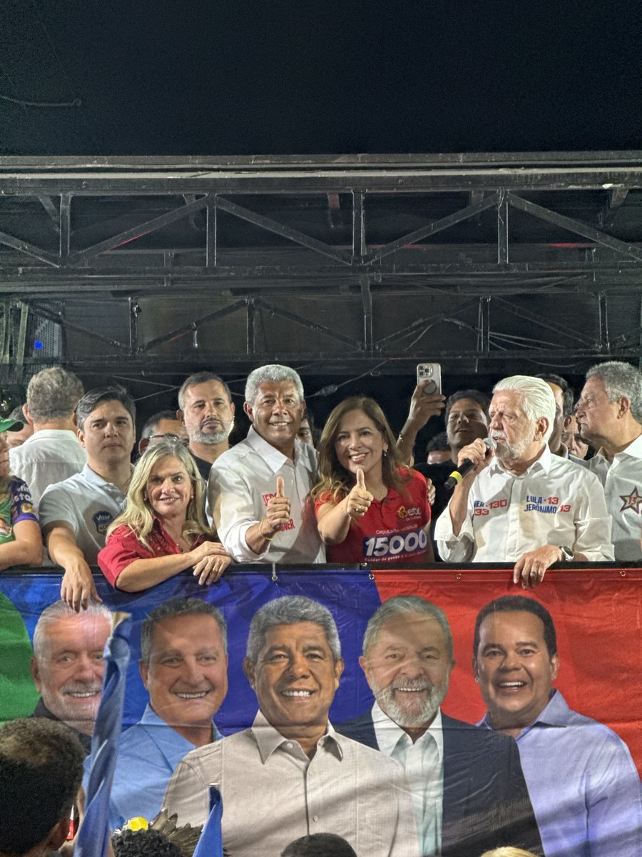 Bete no palanque com o polegar erguido, ao lado de lideranças, durante ato de campanha à noite